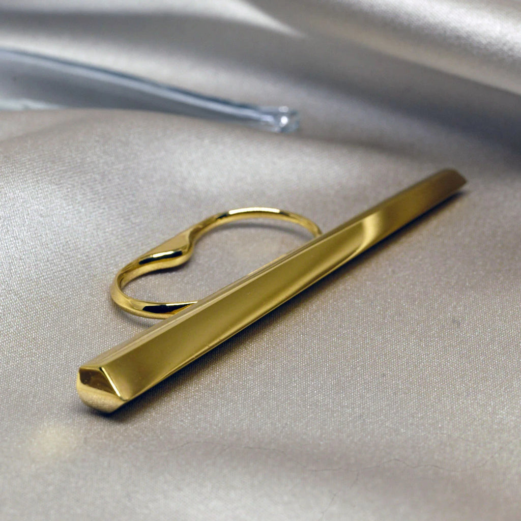 La bague Grand Punch du créateur de bijoux canadien Bena Jewelry, photographié en gros plan sur un tissu satiné. Bague pour deux doigts très confortable disponible chez Ruby Mardi, en ligne ou dans la Petite Italie de Montréal.