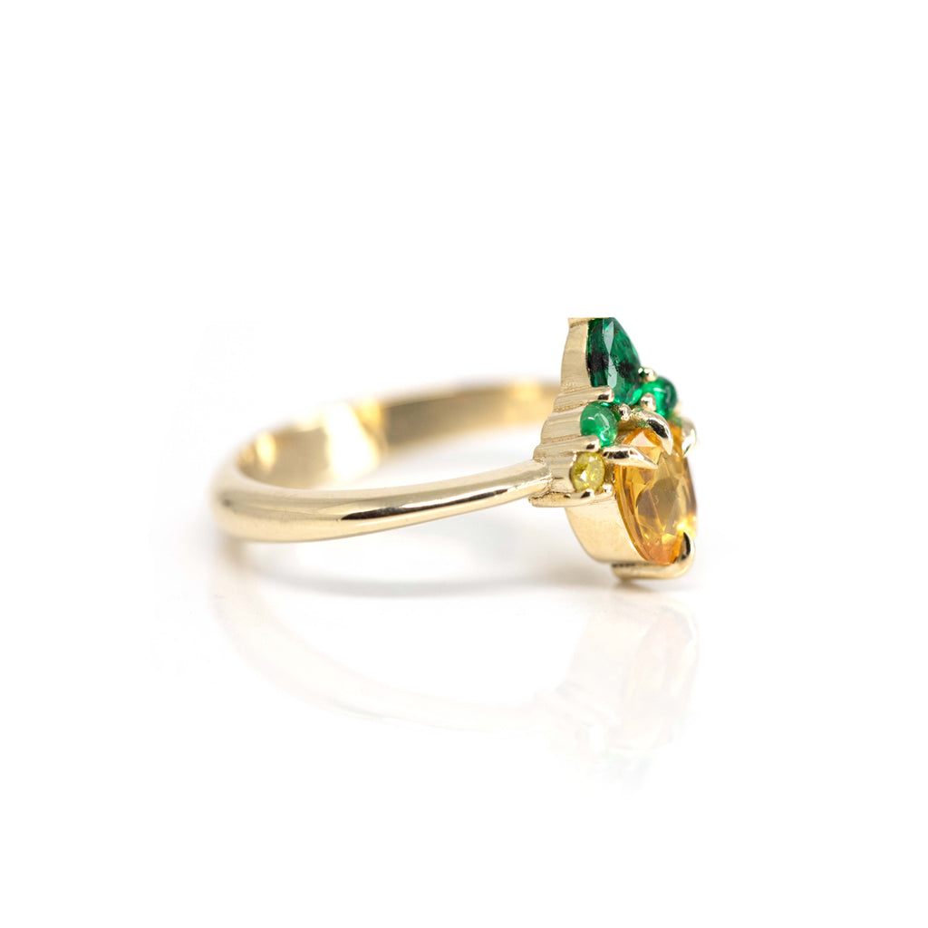 A beautiful jewelry creation featuring yellow sapphire, emerald and diamonds. This engagement ring or right hand ring is photographed from a side view.