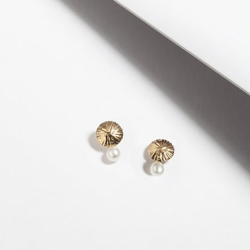 Small dainty fresh water pearl stud earrings handmade in Montreal by Veronique Roy and showing a delicate texture on the sterling silver gold plated part. 
