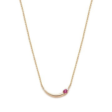 A feminine and asymmetrical gold necklace seen photographed on a white background. The piece of jewelry shows a curved gold detail, a pink tourmaline et a small round brilliant diamond.