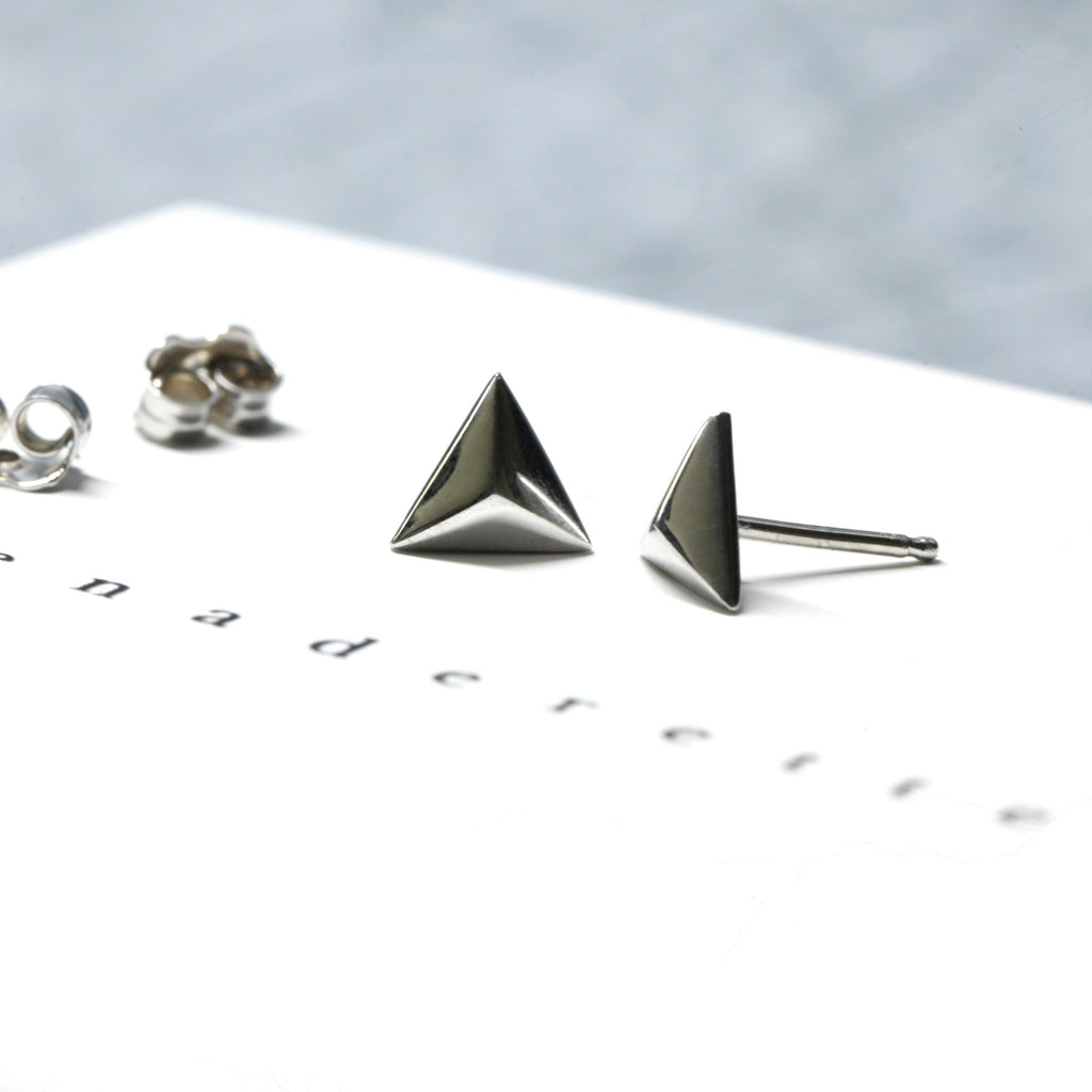 side view of silver studs pyramidal shape unisex style edgy earrings at best jewelry store in montreal boutique ruby mardi on white and blue background