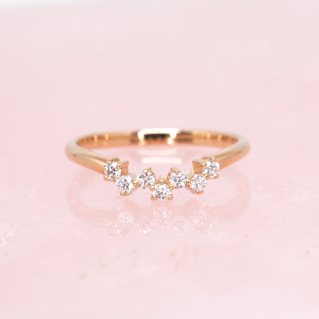Jonc de mariage en or rose avec sept diamants photographié sur du quartz rose. 
