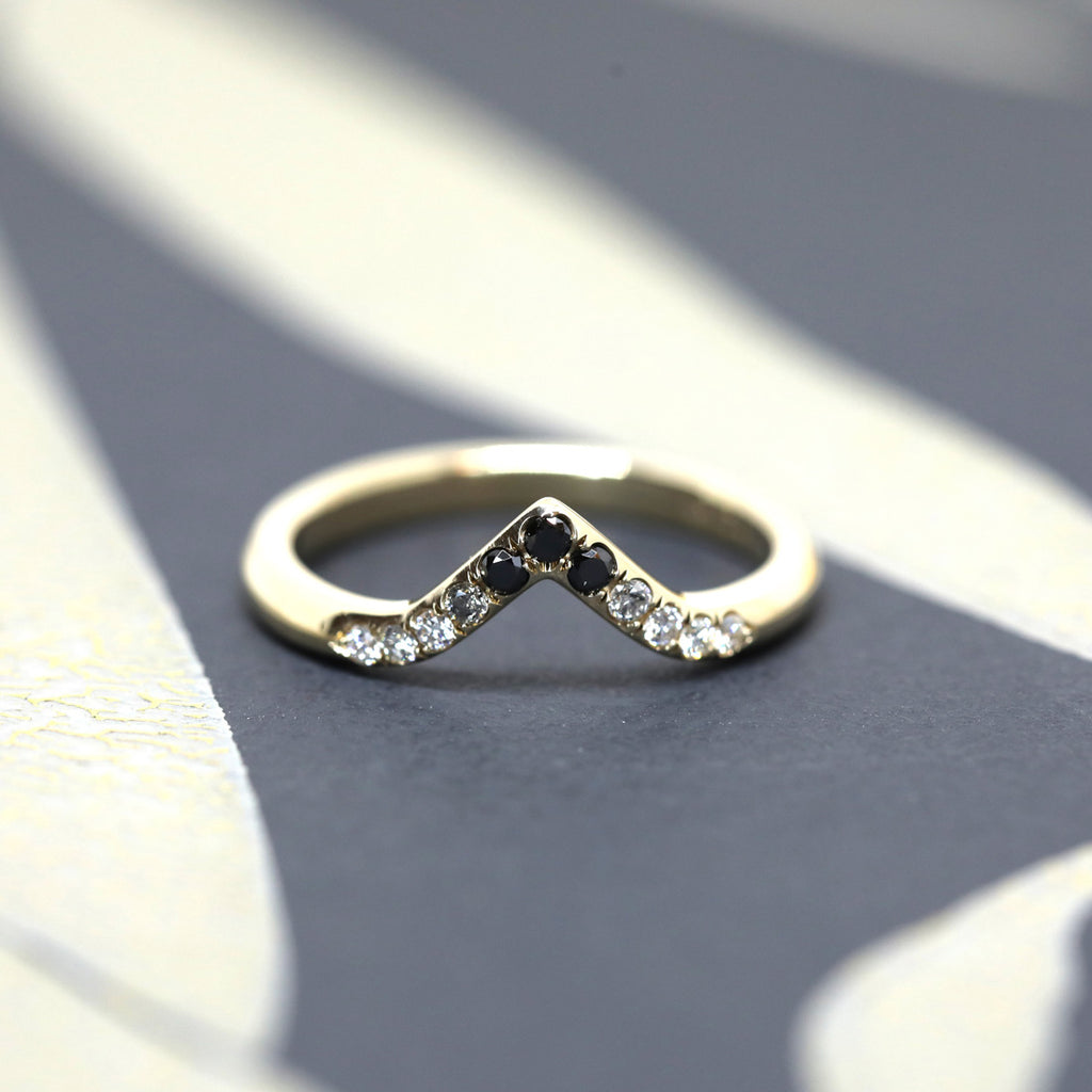 A curved wedding band in yellow gold featuring eleven diamonds in a gradation from white to black. A creation by Yuliya Chorna available at Ruby Mardi, a fine jewelry store showcasing the work of talented Canadian jewelry designers.