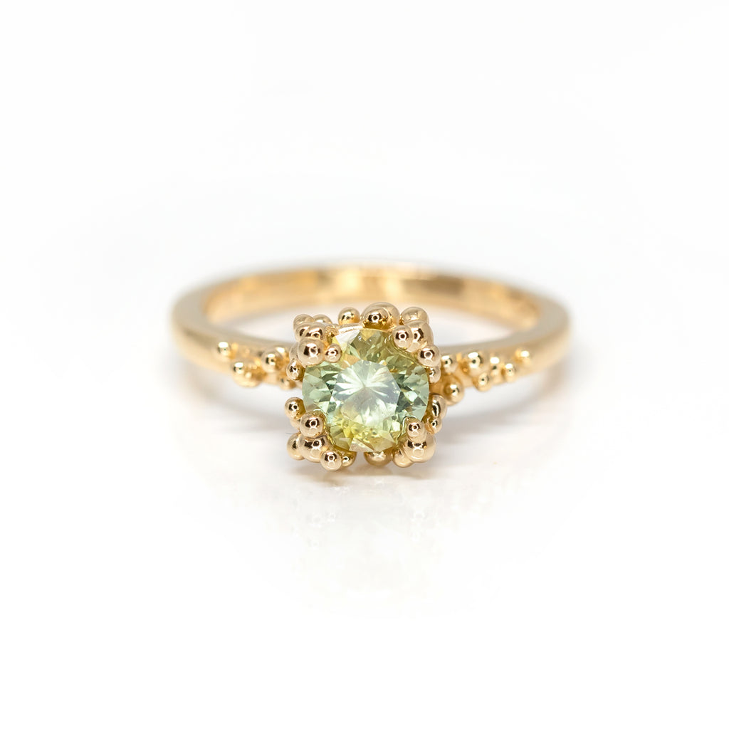 Stunning engagement ring by Meg Lizabet Jewellery photographed on a white background. A yellow gold organic ring with gold granules and encapsulated bicolor sapphire (yellow & green) of 1.08ct. One of a kind ring available only at Ruby Mardi.