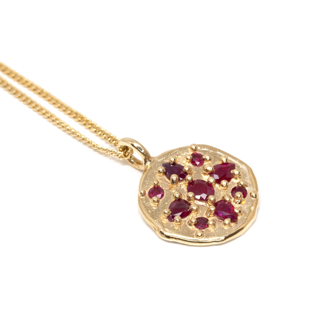 An organic handmade gold pendant medaillion with gold granules and encapsulated rubies. Find this beautiful piece of fine jewelry by Meg Lizabet at Ruby Mardi, a high end jewelry store located in Montreal's Little Italy.