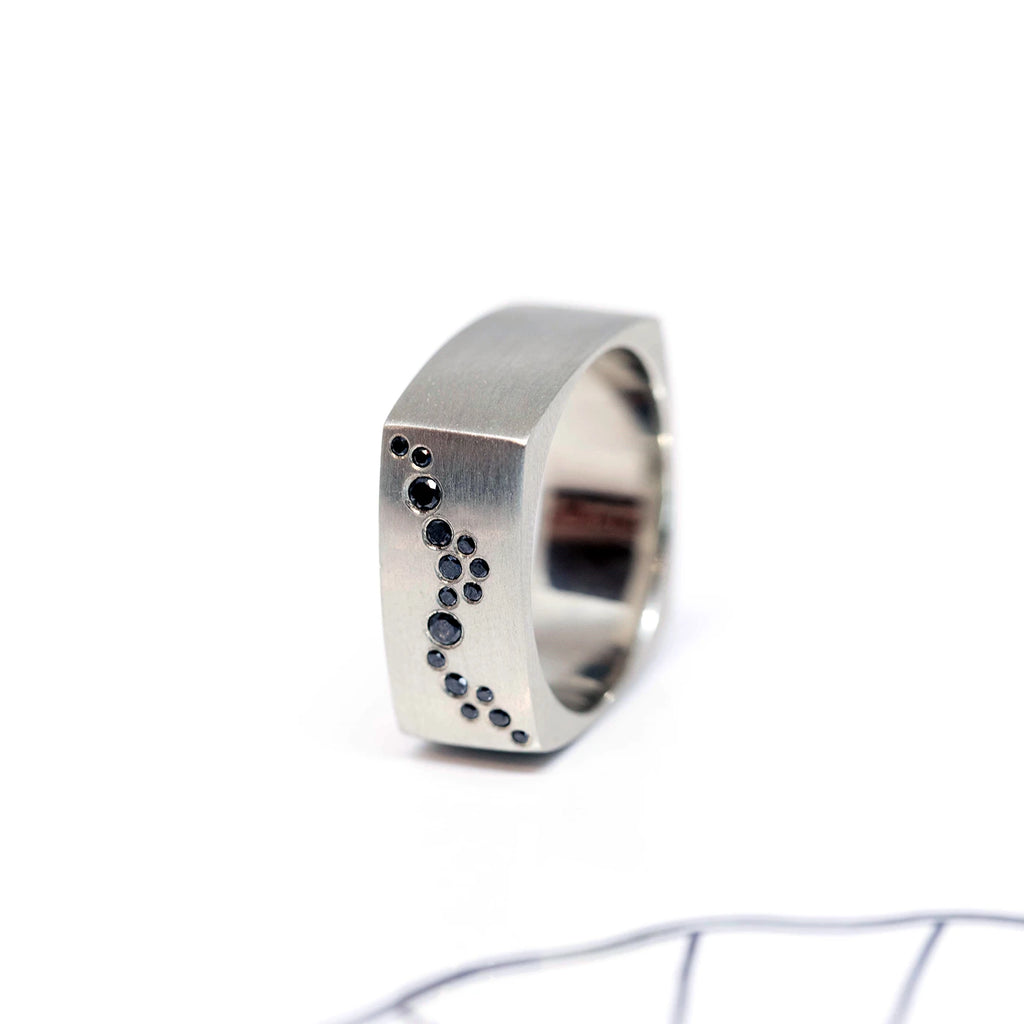 side view of black diamond white gold men wedding band edgy ring bespoke jewellery design by Janine de Dorigny on a white background