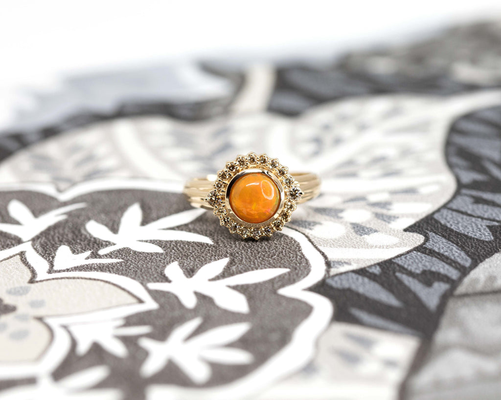 ELENA ring seen on a black & white wallpaper. A statement ring featuring a big orange opal with a natural diamond halo. Fine jewelry handmade in Montreal and available online for worldwide shipping. 