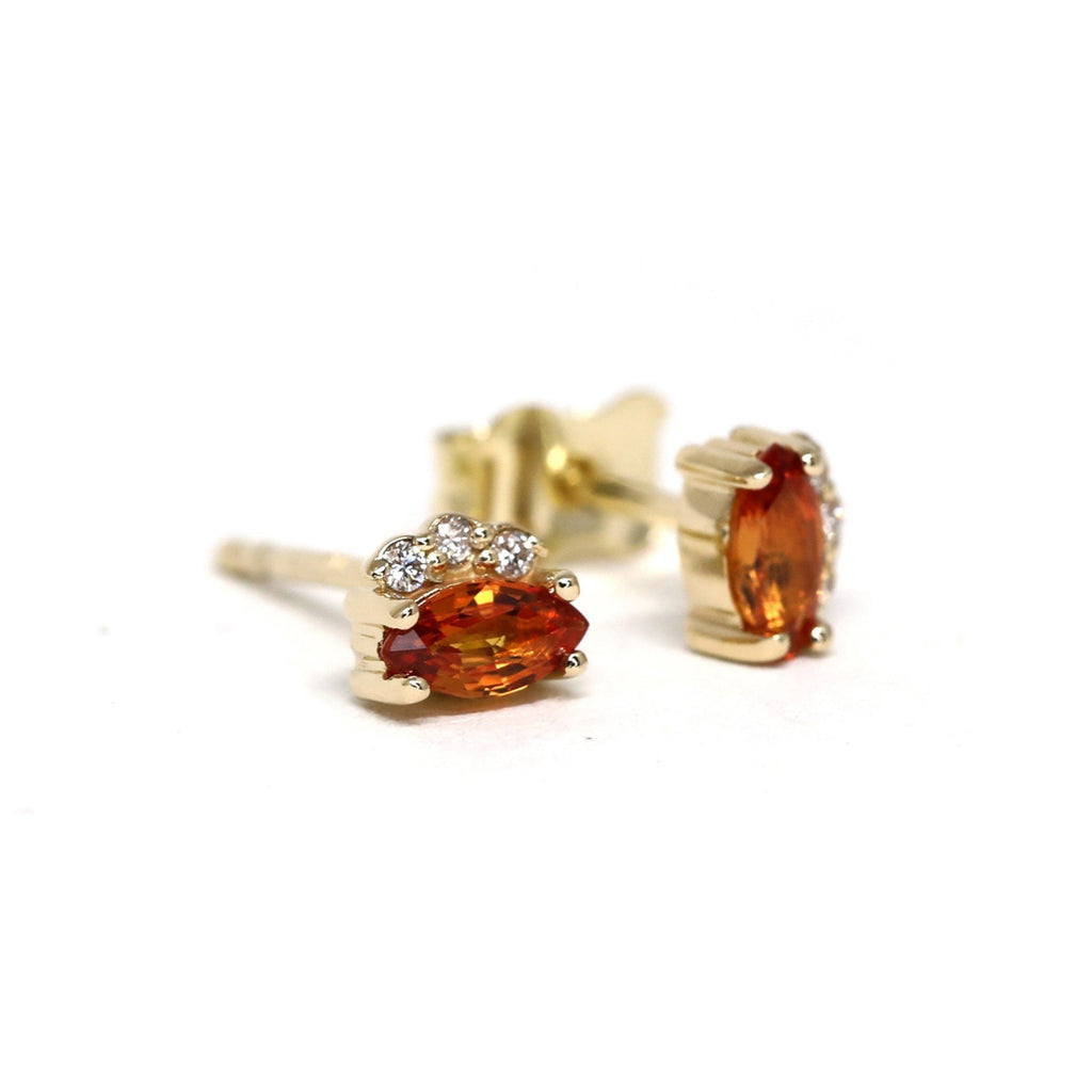 Orange Sapphire Earrings with 3 small diamonds on a white background. Sapphire gemstone stud gold earrings created by Ruby Mardi, a fine jewelry store in Montreal's Little Italy that specializes in engagement rings and custom jewelry creations in Montreal. 