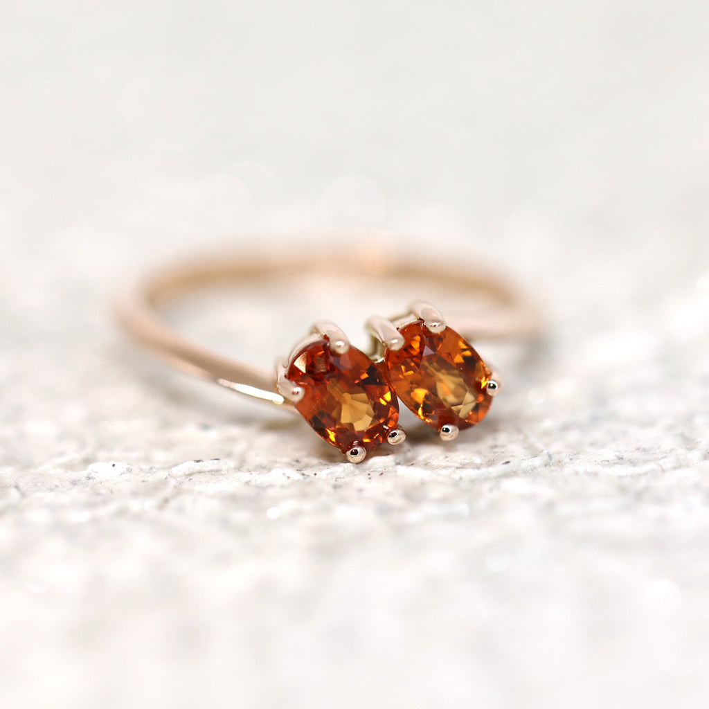 Product photography of a toi & moi spessartite garnet ring in rose gold by designer Bena Jewelry. The perfect symbolic engagement ring. Find the most exquisite designer jewelry at Ruby Mardi, a fine jewelry store in Montreal that presents the work of the most talented Canadian jewelry designers. Custom jewelry services also offered.