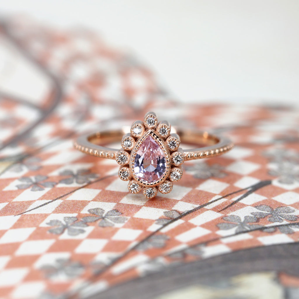 Front view of Emily Gill's ring made with a pink sapphire and a delicate miligrain handmade halo that gives a vintage touch while remaining modern. This original finals ring is available at the Ruby Mardi jewelry store in Montreal.