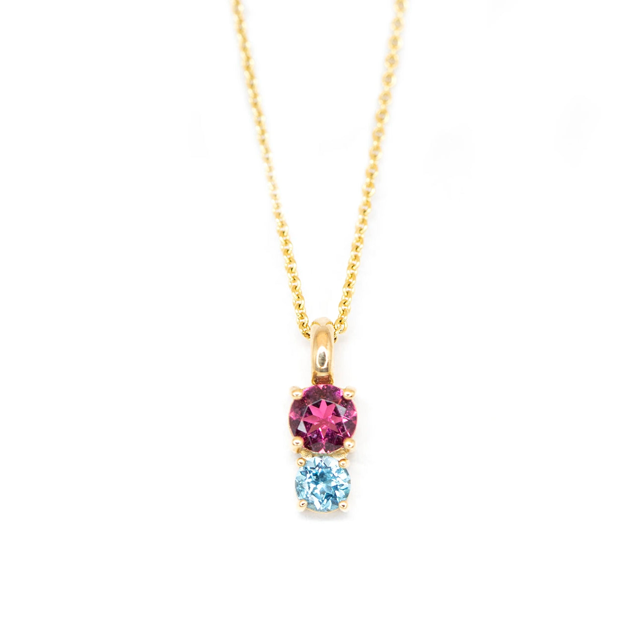 Independent jewelry designer Lico, based in Montreal, presents this yellow gold pendant with two colored gems, including a pink tourmaline and a round sky blue topaz. This minimalist fine jewelry is available for sale at Ruby Mardi, the best jewelry store in Montreal and specialized in fine jewelry from Canadian artisan jewelers.