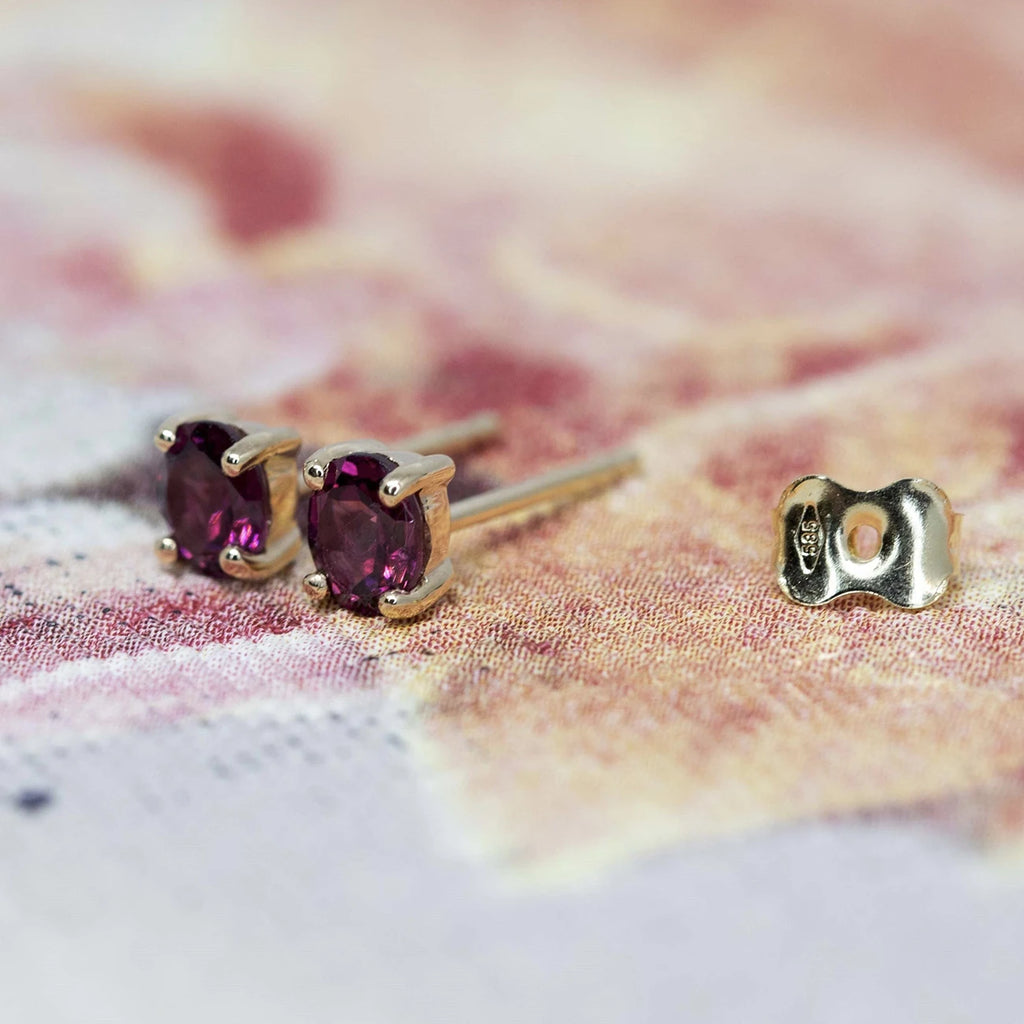 side view of oval shape red garnet stud earrings yellow god minimalist fine jewellery montreal made boutique ruby mardi jeweler on a red and multi color background