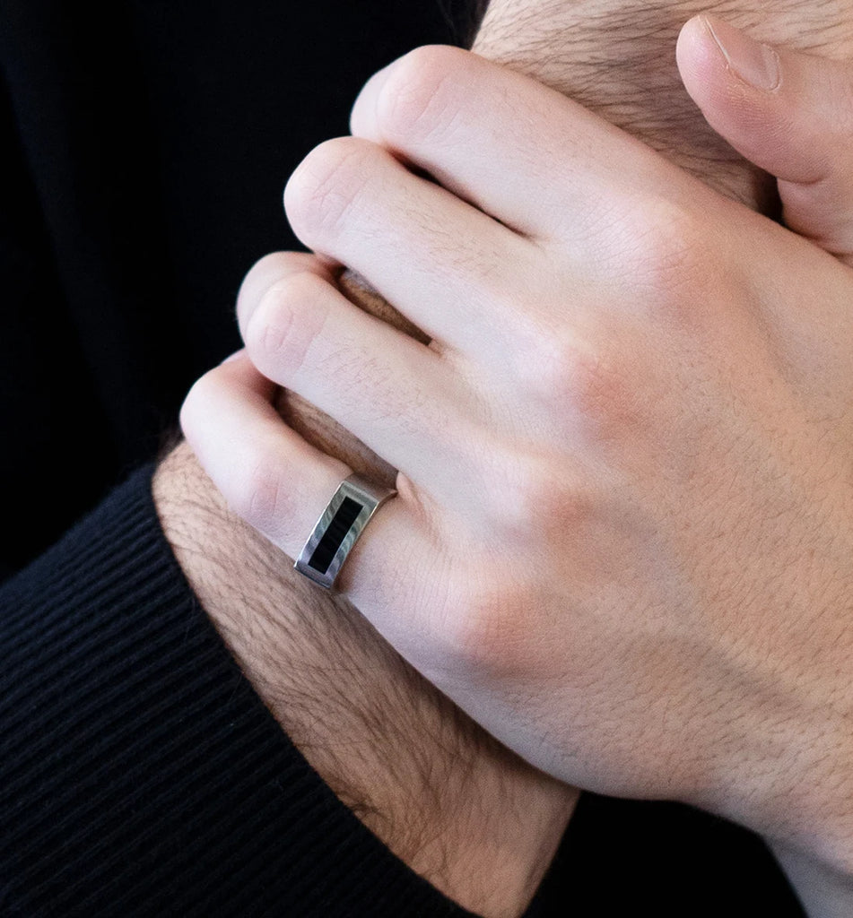 men hand wearing a white gold ring with onyx gemstone bespoke jewel by the best canadian designers at the gallery boutique ruby mardi jeweler on a dark background