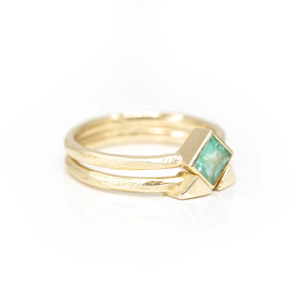 side view of matching yellow god engagement ring with a emerald gemstone handmade by the bespoke jewelry designer sheena from montreal for boutique ruby mardi on a white background