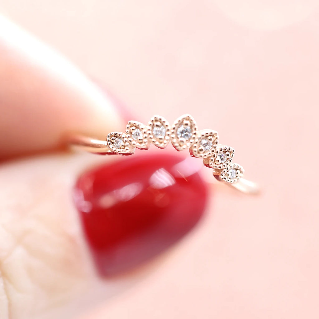 hand of girl rose gold milgrain diamond wedding engagement ring made in montreal at the best bridal jeweler on orange background