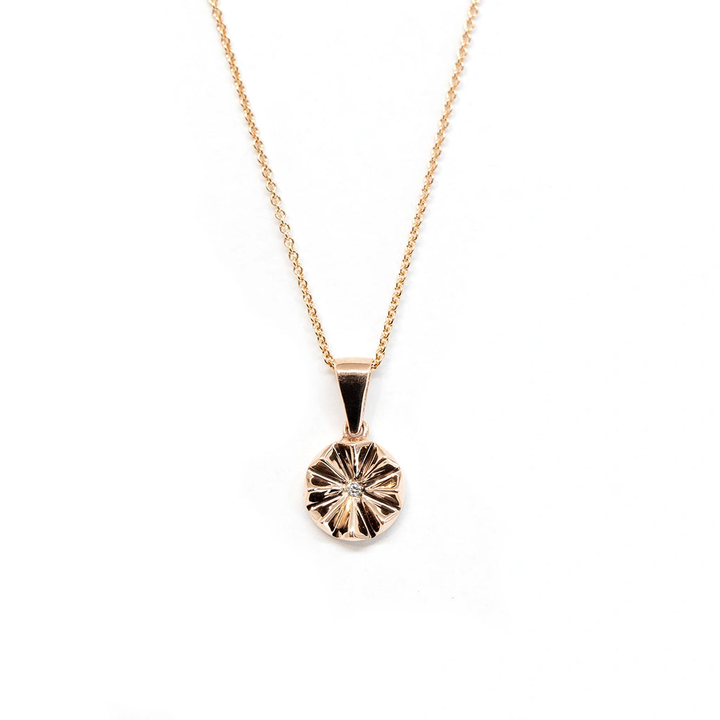 Rose gold round pendant with a central labgrown diamond seen on a white background. Fine jewelry made in Montreal by jewelry store Ruby Mardi for the Montreal CHUM Foundation.