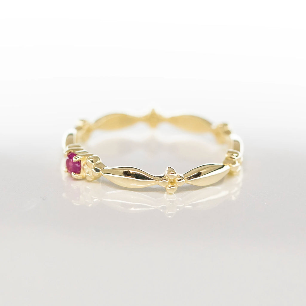 side view of a yellow gold ruby ring custom made ring by artisan designer Sheena Purcell made in montreal for the jeweller ruby mardi on a pink background