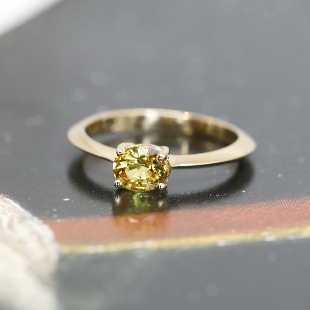 front view of oval shape yellow sapphire gold engagement ring custom made minimalist bridal jewels made by the best jewelry store boutique ruby mardi on a dark background
