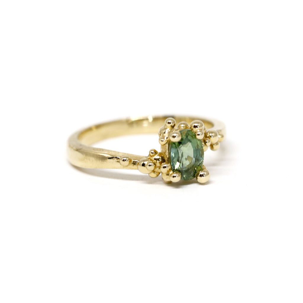 Baleal ring on a white background by Toronto-based jewelry designer Meg Lizabet. Organic ring with hand-placed gold granules. 14K yellow gold ring with encapsulated green Montana sapphire. Ethical gemstone. Unique ring that cannot be reproduced. Find Meg Lizabet's creations in Montreal at Ruby Mardi, a boutique-gallery in Montreal's Little Italy, not far from Rosemont, Villeray, Outremont, Mile End. Custom jewelry design services in Montreal also available.