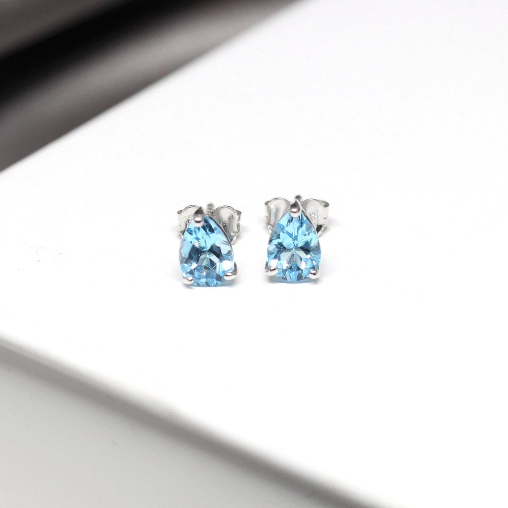 top view of pear shape topaz gemstone studs cusotm made sky blue gems silver earrings jewels on white background