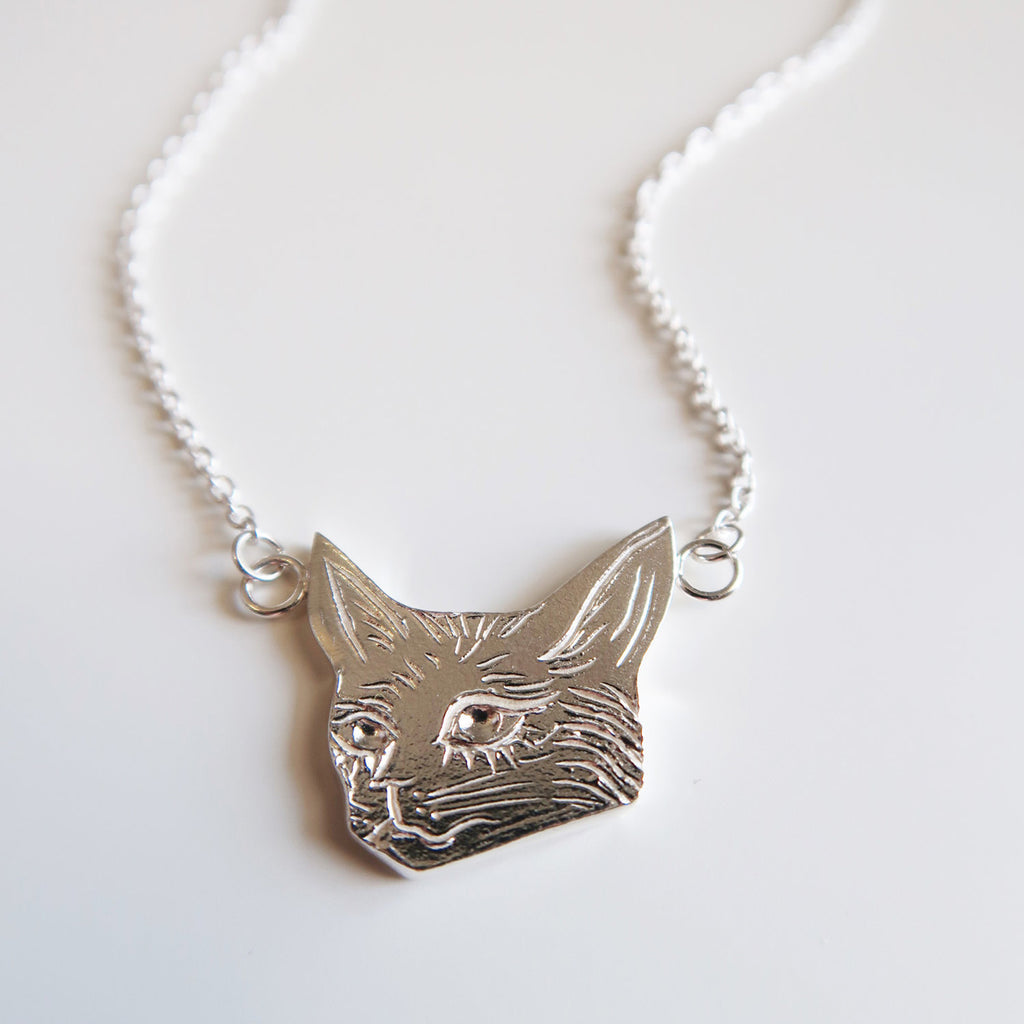 Cat head pendant in sterling silver handmade in Toronto by Invidiosa Jewelry and available in Montreal at Ruby Mardi.