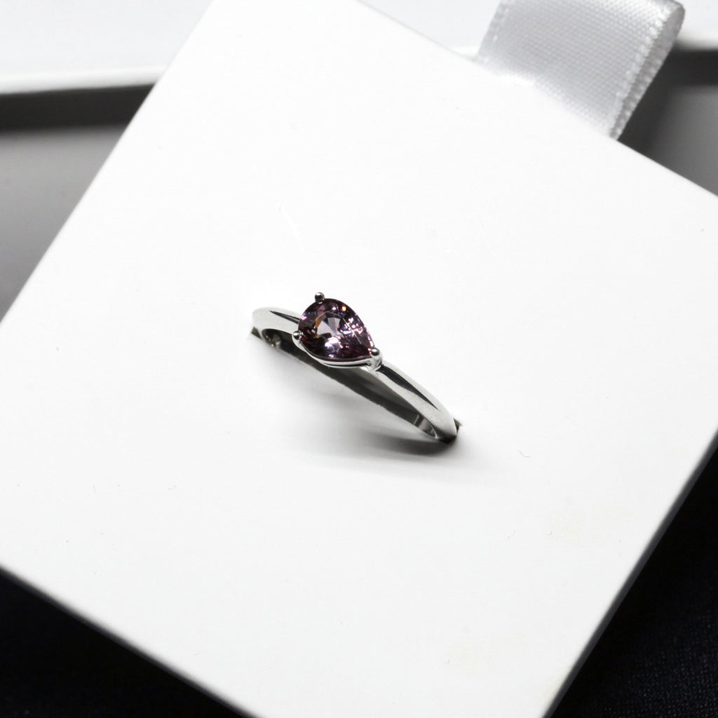 top side view of deep purple pear shape white gold engagement ring custom made in montreal by the fine jeweller ruby mardi in little italy on a white background