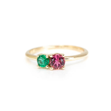 This you and me ring is made by jewelry designer Lico. Made in yellow gold with colored gems in round shapes of green, with an emerald and pinkish purple with a tourmaline. This minimalist bridal jewelry is available for sale at the Ruby Mardi fine jewelry store located in Montreal.