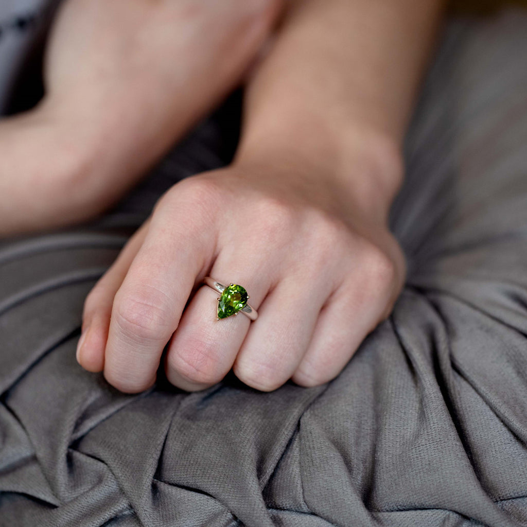 Statement ring in silver and gold featuring a big natural green gemstone (peridot) worn by a lady. Find this modern ring and other pieces of jewelry at our jewelry store in Montreal, or at our online store.