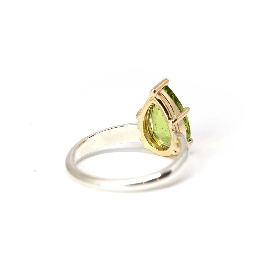 Product photography of a beautiful ring in 14k yellow gold and sterling silver featuring a huge natural green gem, peridot, by designer Bena Jewelry. Find the most exquisite designer jewelry at Ruby Mardi, a fine jewelry store in Montreal that presents the work of the most talented Canadian jewelry designers. Custom jewelry services also offered.
