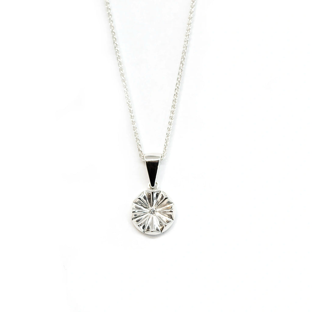 Sterling silver round pendant with a central labgrown diamond seen on a white background. Fine jewelry made in Montreal by jewelry store Ruby Mardi for the Montreal CHUM Foundation.
