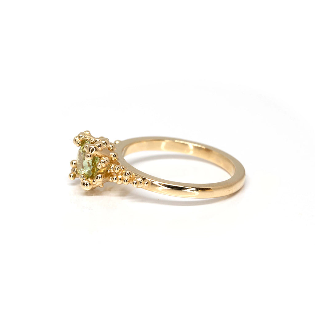 Stunning engagement ring by Meg Lizabet Jewellery photographed on a white background. A yellow gold organic ring with gold granules and encapsulated bicolor sapphire (yellow & green) of 1.08ct. One of a kind ring available at fine jewelry store Ruby Mardi in Montreal.