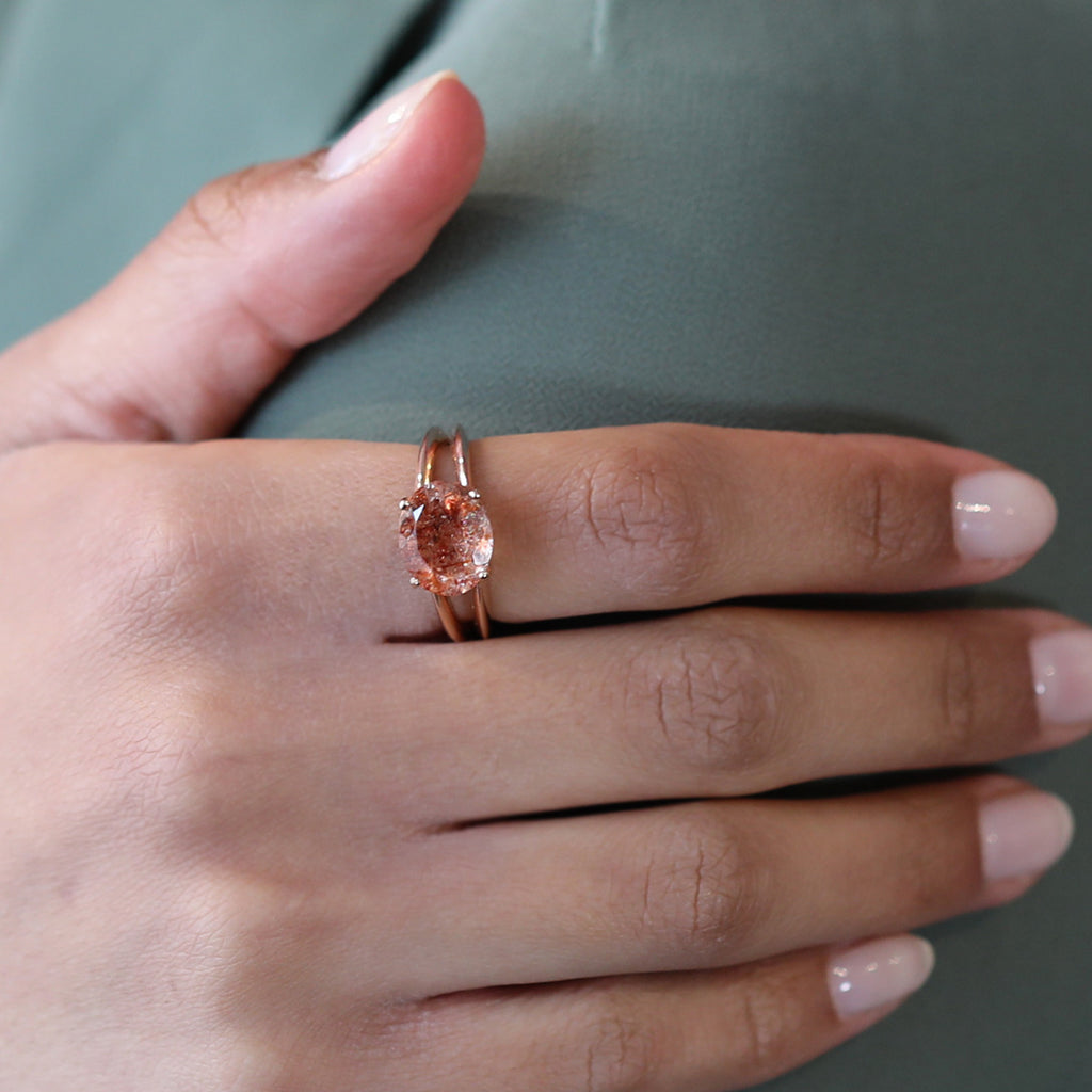 Statement ring in rose gold featuring a big natural sunstone of an oval shape worn by a lady. Find this modern one-of-a-kind ring and other unique pieces of jewelry at our jewelry store in Montreal, or at our online store.