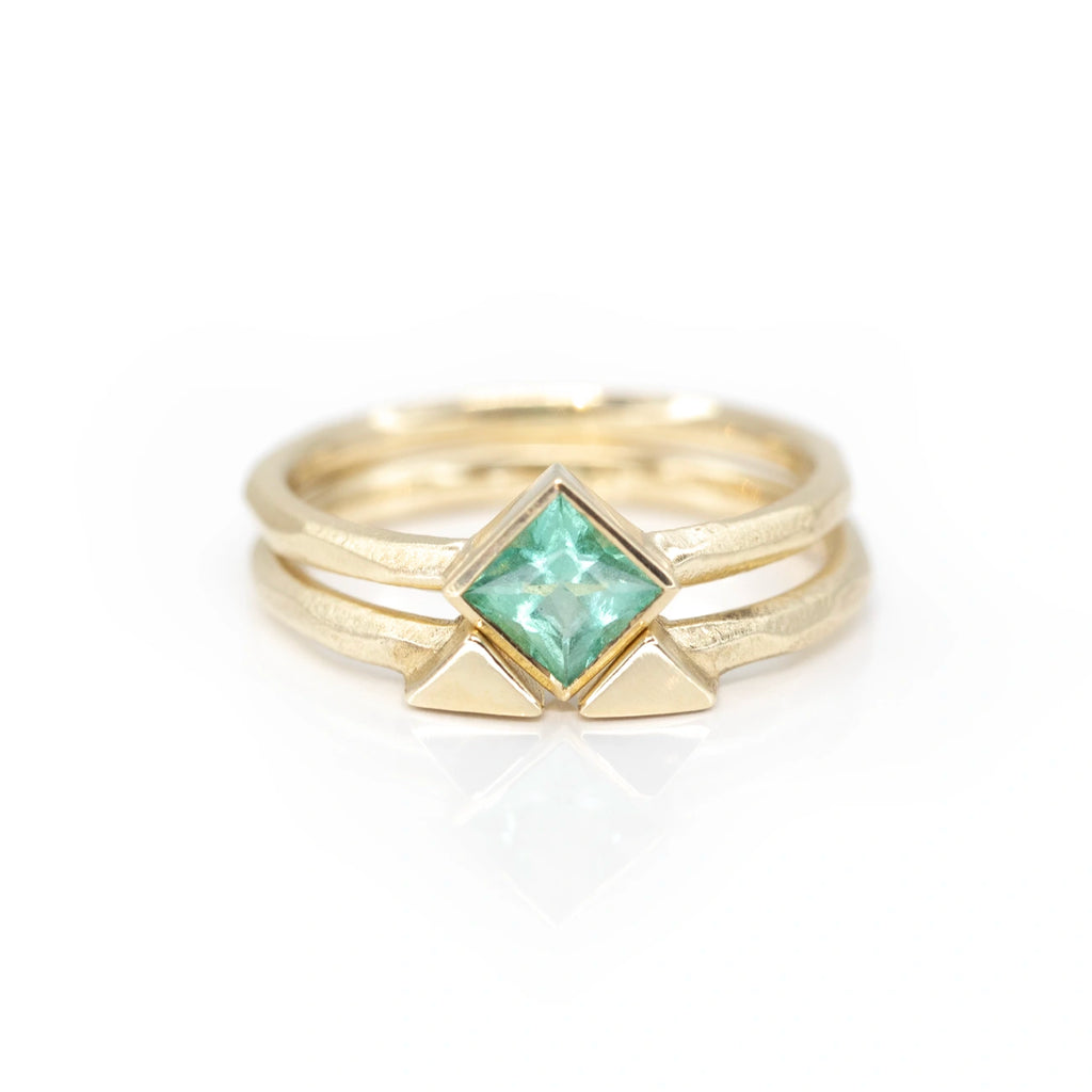princess cut emerald yellow gold designer engagement ring custom made in montreal by the artisan sheena with its matching band on a white background