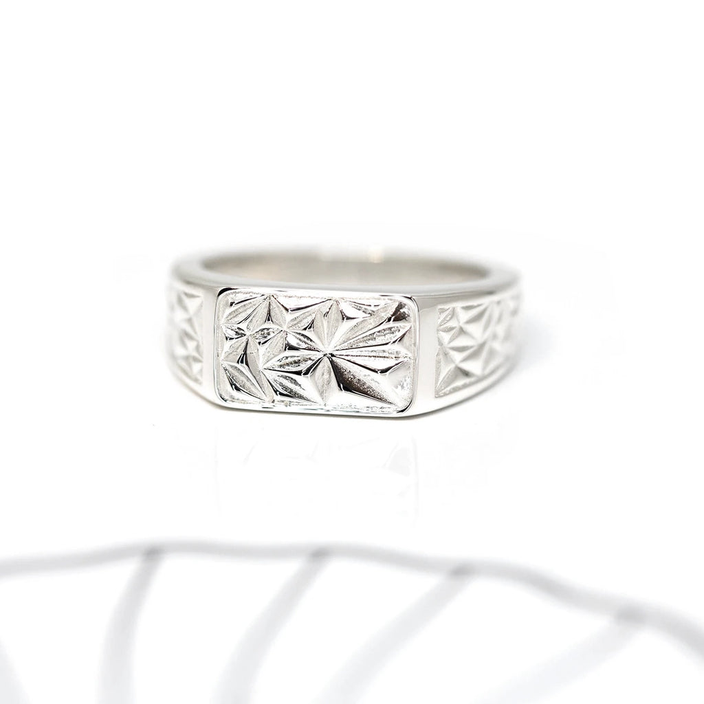 Signet edgy bold men ring made in sterling by Bena Jewelry in Montreal. This local brand designs chiseled jewels and other statement gender neutral pieces. Seen here on a white background with small lines detail. 