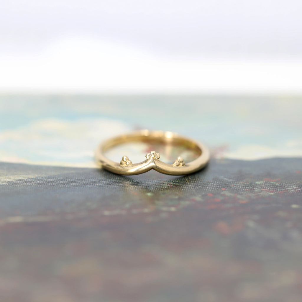 Yellow gold band in V shape with chevron photographed on a romantic background. Alternative organics wedding jewelry that can be found at fine jewellery boutique Ruby Mardi in Montreal’s Little Italy.