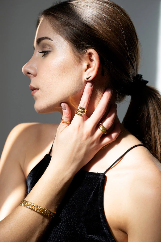 A young and elegant lady is wearing many gold vermeil jewels by Montreal brand Bena Jewelry. All these pieces (earrings, bangles and gender neutral rings) are available at fine jewellery store Ruby Mardi in Little Italy.