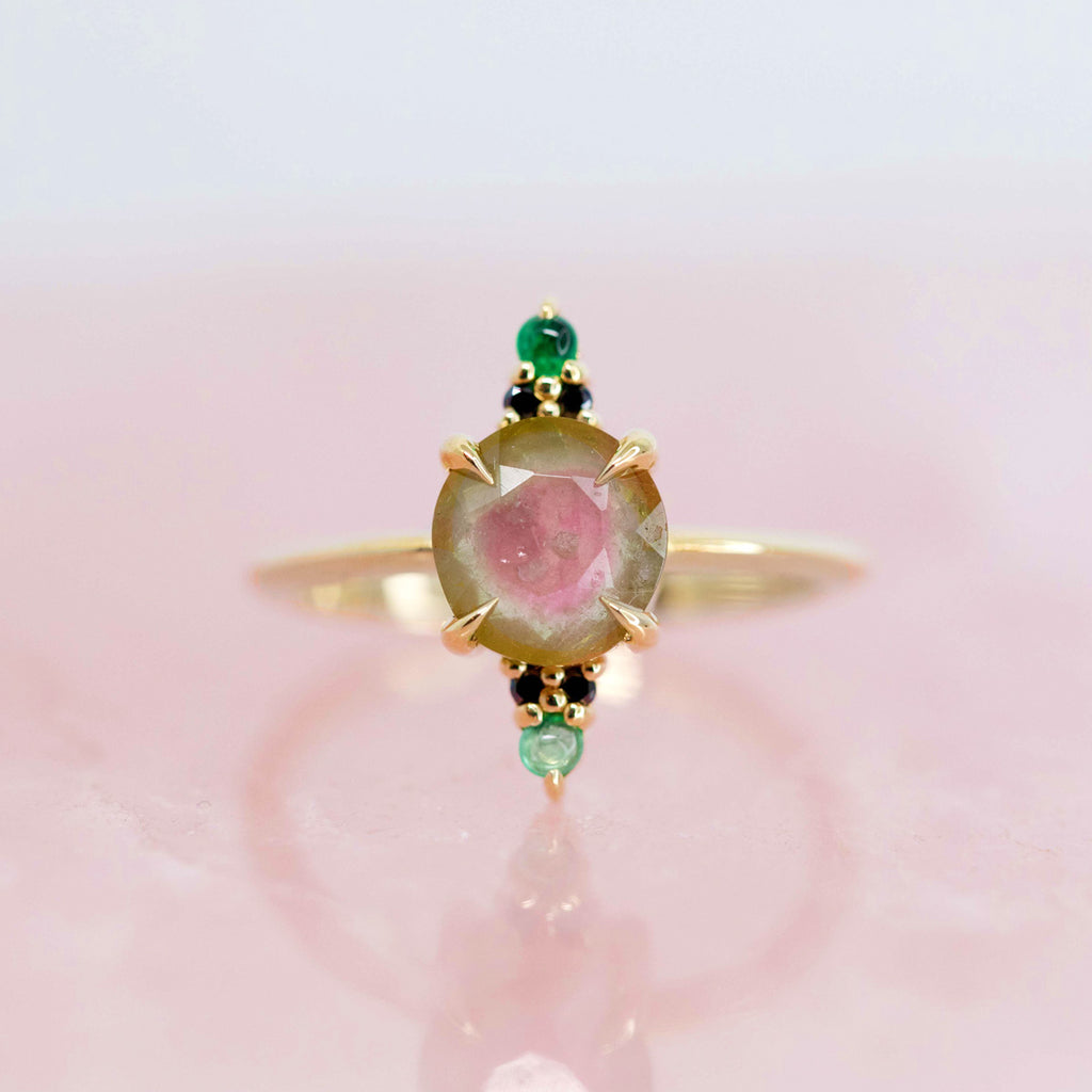 A multi gemstone yellow gold ring photographed in close up on a rose quartz background. Handmade jewelry piece by Nadia Werchola in Toronto, available in Montreal at high end store Ruby Mardi.