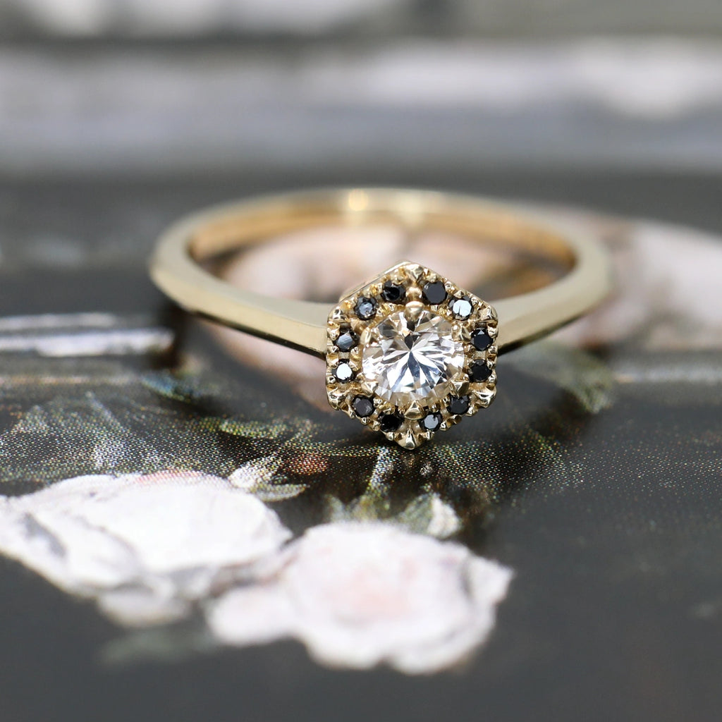 custom made designer engagement ring in yellow gold with a round white natural sapphire gemstone and black diamond montreal best jewelry store designer by Liane Vaz on dark multi color background