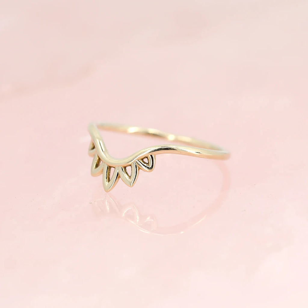 Unique handcrafted floral contour gold band photographed over a natural rose quartz. This cool jewellery piece can be found at Ruby Mardi, a fine jewelry store that sells one-of-a-kind engagement rings in Montreal.