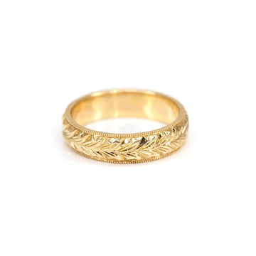 yellow gold engraved wedding band fine jewelry made in motnreal by deborah lavery canadian designer at the best jewellery store in montreal on a pink background