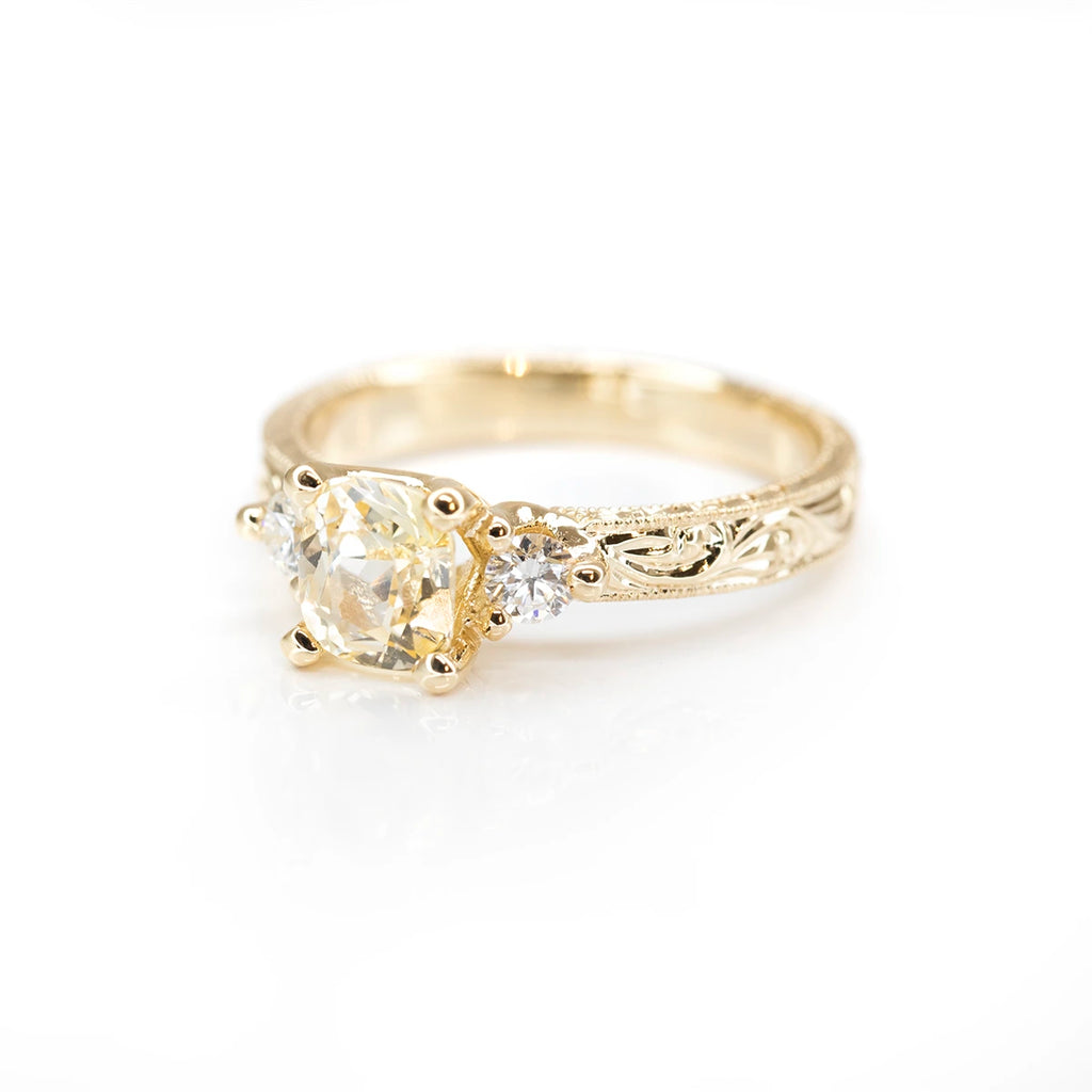 side view of engraved yellow gold diamond ring and cushion yellow sapphire natural gemstone fine jewelry designer bridal jewellery montreal best jeweler ruby mardi on a white background