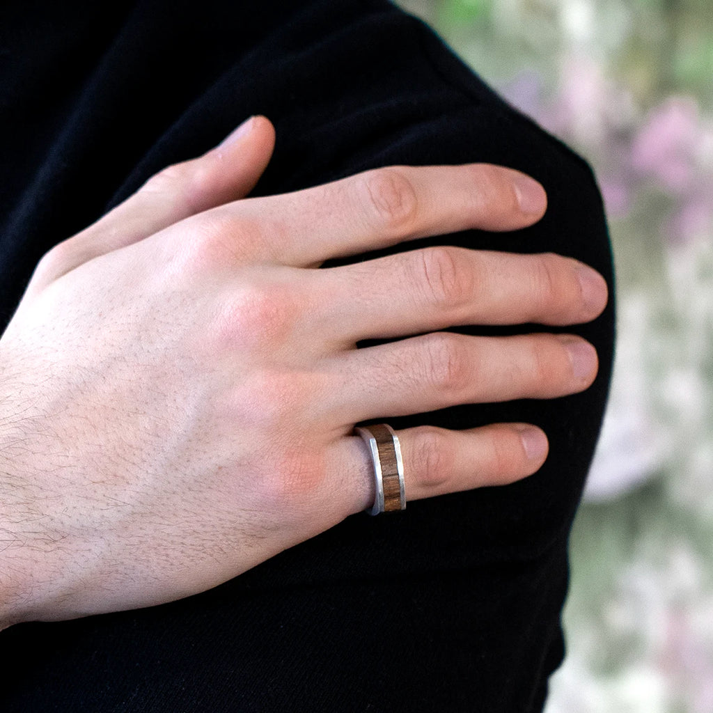 men wearing a silver ring with wood included inside custom made by the artisan designer Janine de Dorigny for boutique ruby mardi fine jeweler in montreal on a multi color background