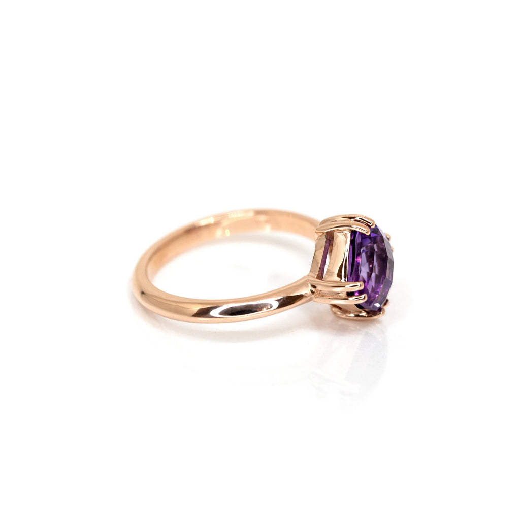 Side view of a rose gold statement ring with a purple gemstone (a cushion cut amethsyt) handmade by designer bena jewelry in Montreal, photographed on a white background.