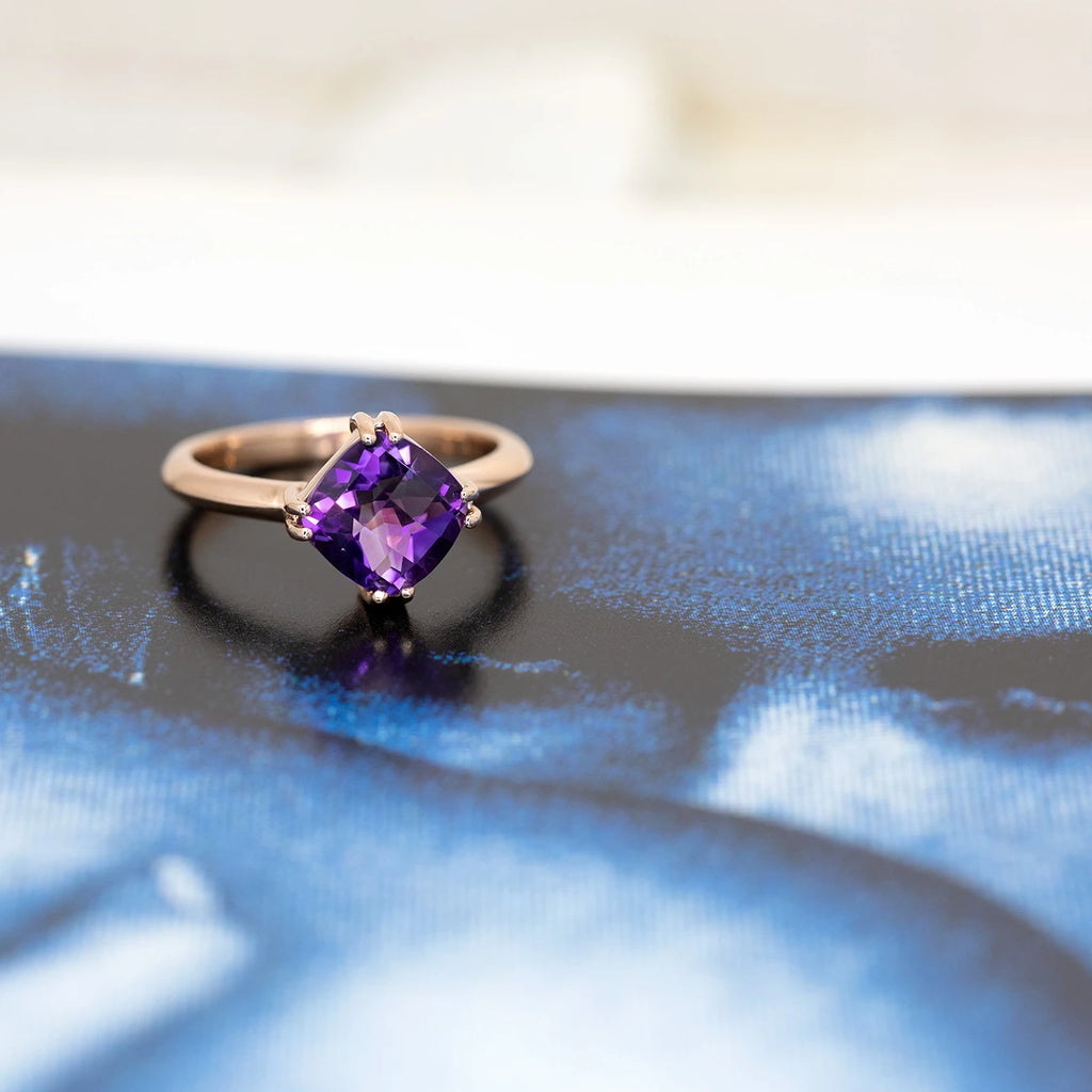 Rose gold ring featuring an amethyst seen on a white and blue background showing a couple in love. This statement ring was designed and made in Montreal by designer Bena Jewelry and is sold at jewelry store RUBY MARDI in Little Italy.