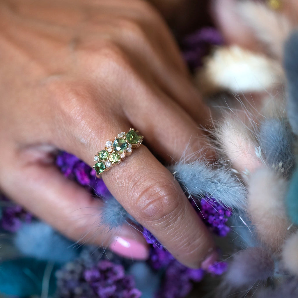girl wearing a green gemstone sapphire garnet and diamond bridal ring hold blue flowers