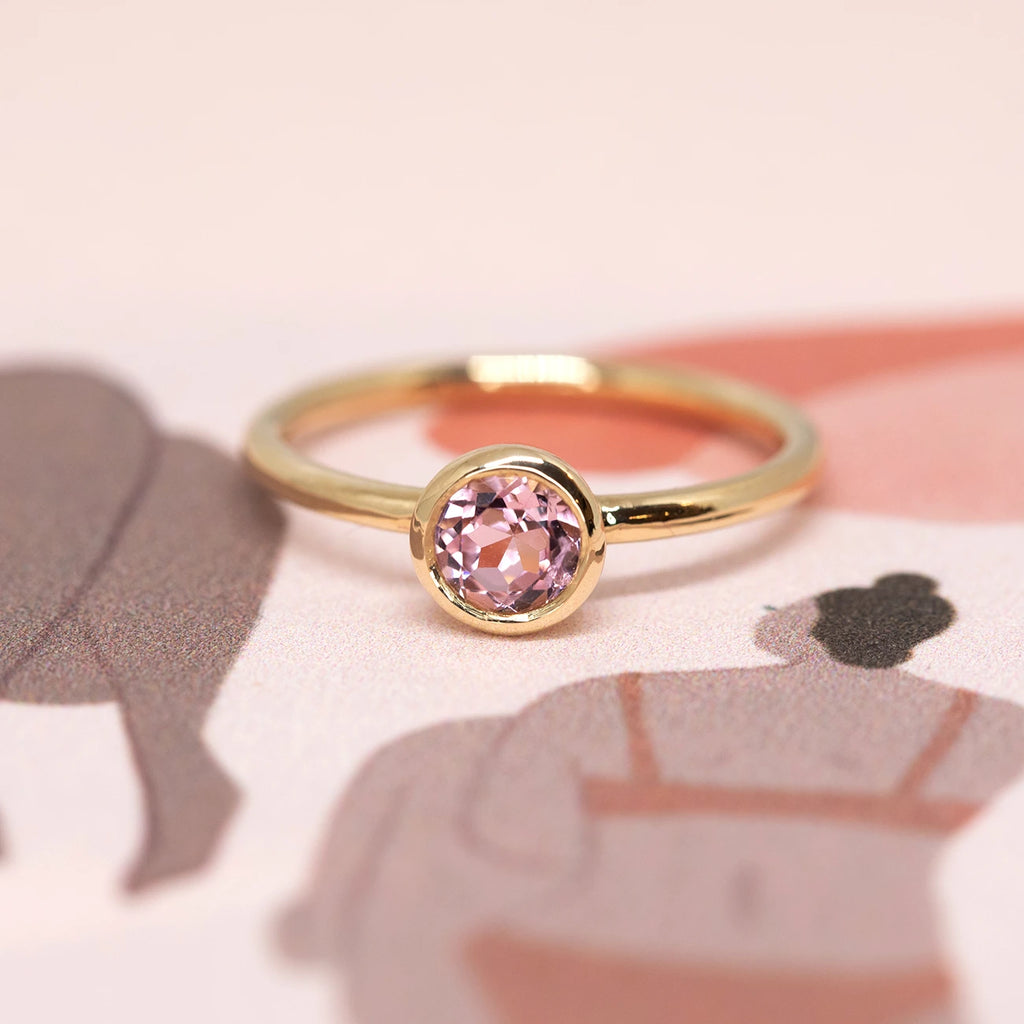 bezel setting pink tourmaline yellow gold custom made engagement ring in montreal by the designer sheena for boutique ruby mardi in montreal on pink background