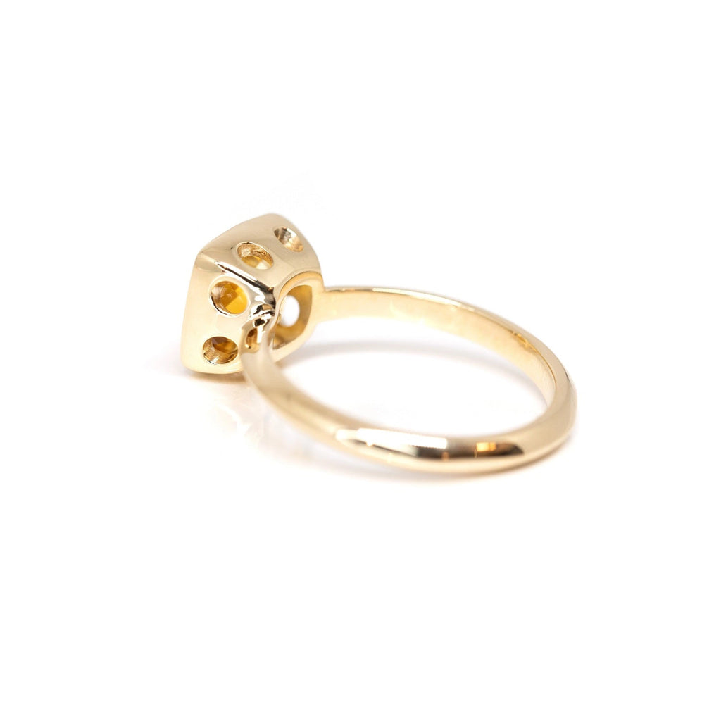 Back view showing round opening details of a bezel set yellow gold ring seen on a white background.