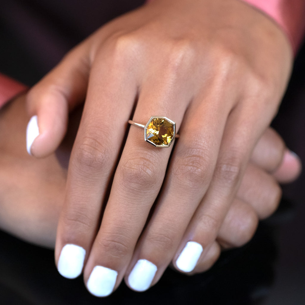 Statement ring in yellow gold featuring a big natural citrine in a fancy shape worn by a lady. Find this modern one-of-a-kind ring and other unique pieces of jewelry at our jewelry store in Montreal, or at our online store.