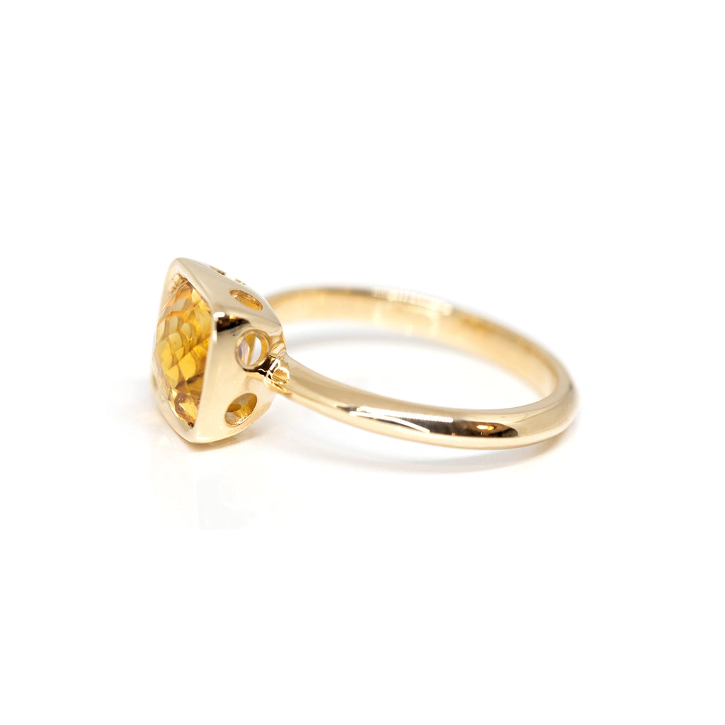 Side view of a yellow gold ring with a bezel setting featuring a cushion cut citrine, seen on a white background. This ring was handmade and designed by Bena Jewelry in Montreal.