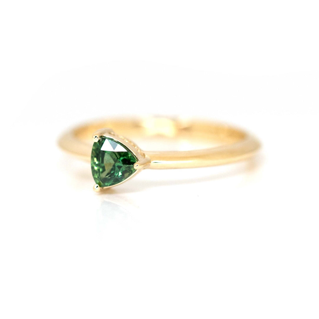 Engagement ring made with a trillion-shaped green sapphire mounted on yellow gold with a simple and minimalist style. Bridal ring with an edgy twist is made in Canada at Montreal's finest jewelry store Ruby Mardi.